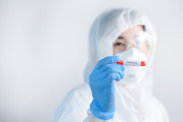 Selective focus of Corona virus blood sample in doctor hand in PPE suit.