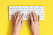 © Katarina - Top view on female elegant hands on a computer keyboard isolated yellow background and clipping. Assistance service respond on e mail.