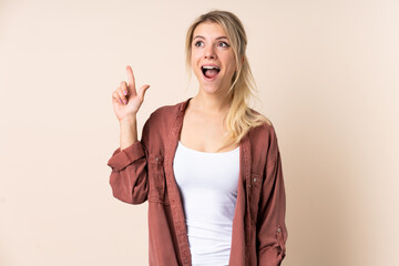 Blonde woman over isolated background pointing up and surprised