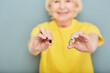 Variety hearing aids for treatment of deafness for older people in elderly woman's hands over grey background, soft focus