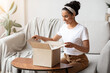 © Prostock-studio - Happy young woman unpacking delivery box, home interior