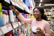 © Prostock-studio - Happy young black woman shopping in beauty department of big supermarket, choosing personal care products