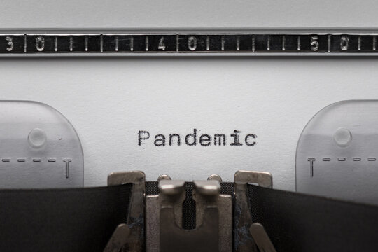 Typing text PANDEMIC on vintage manual typewriter. Close up of writes word on white paper. Shot in macro. Concept of Coronavirus COVID-19.