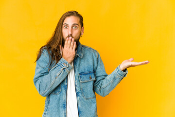 Young man with long hair look impressed holding copy space on palm.