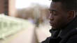 © Marco - Anxious young black man suffering emotional pain sitting on sidewalk in street