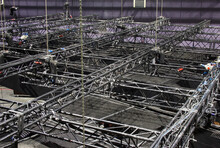 Black Steel Trusses Are Lifted By Chain Hoists. Installation Of Professional Rigging Equipment For A Concert Show.