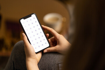Young women holding her phone in in hand, reading news, browsing internet or digital application, watching video, with white coffee on the table