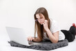 © Andriy Medvediuk - A seriously young girl in glasses sits with a laptop. Education, remote work and blogging. Isolated on a white background.