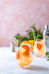 Wall Mural - Tequila cocktail or cold lemonade with grapefruit juice, tinted with the aroma of a fresh sprig of rosemary