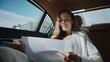 © stockbusters - Cheerful business woman analysing statistics in documents in automobile.