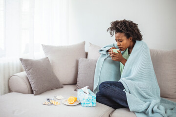 Sickness, seasonal virus problem concept. Woman being sick having flu lying on sofa drinking tea. Sick woman lying in bed with high fever. Cold flu and migraine.