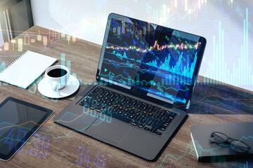 Poster - Online stock market business concept with black laptop on dark wooden office table with coffee and financial graphs and stock market lines. Double exposure