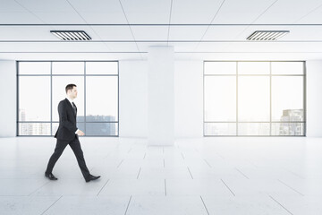 Poster - Businessman in motion in light empty spacious hall room with windows and city view