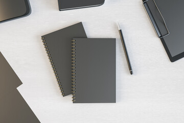 Poster - Blank black sketch books cover with pen on light office wooden table. Mockup