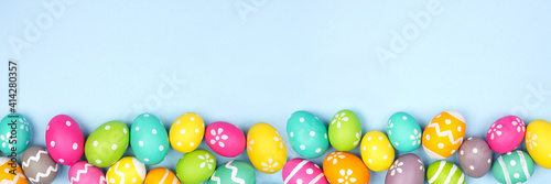 Obraz Dibond Colorful Easter Egg bottom border over a pastel blue paper banner background. Copy space.