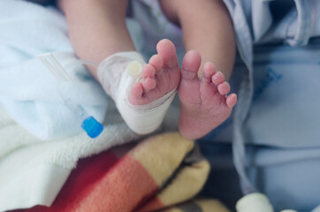 Wall Mural - newborn baby's leg wrapped in a cotton swab and a needle for medication.