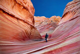 Fototapeta  - Man tourist hiking in Arizona canyon with textured red walls. The Wave, Paria Canyon. Kanab. Utah. United States of America 