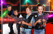 © JackF - Positive teenage boy and girl with laser guns having fun with adults in dark lasertag labyrinth. Focus on boy
