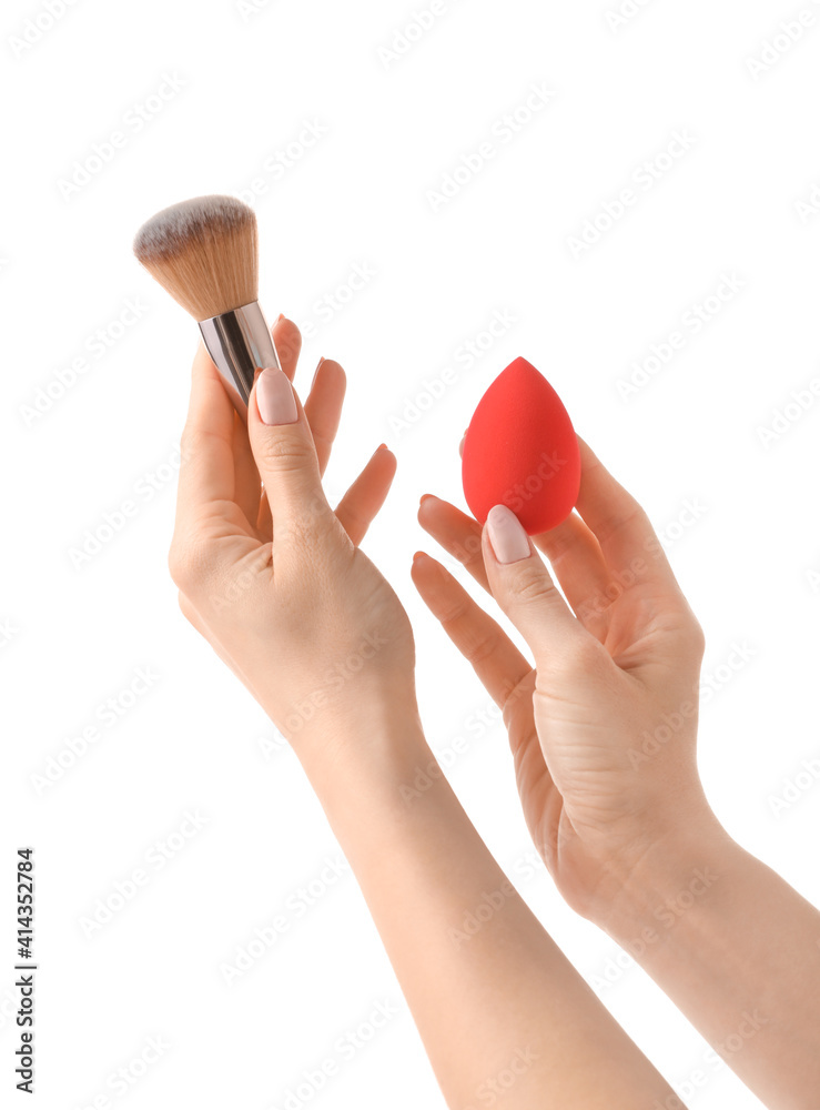 Hands with makeup sponge and brush on white background