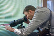 © Maxim - Detective holding camera photographing through blinds at house