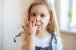 © Татевик Багдасарян - little blonde cute girl got her chocolate fingers dirty and licks them.