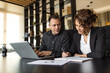 © bnenin - Businesswoman writing in notebook and colleague looking at it.