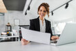 © bnenin - Woman with curly hair using laptop, while holding one document.