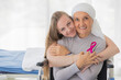 © Bangkok Click Studio - A middle-aged breast cancer woman with clothing around her head effected from chemo therapy sitting on wheel chair and hold hand of her daughter with hope and trust in love.