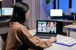 © DC Studio - Entrepreneur talking in the course of online meeting with colleagues doing overtime. Woman working on finance during a video conference with coworkers at night hours in the office.