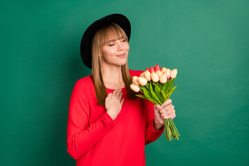 Poster - Photo of charming lady hold bunch tulips close eyes palm chest wear headwear red dress isolated green color background