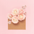 Ranunculus flowers in envelope on pink background. Holiday, greetings, love, romantic concept. Flat lay, copy space