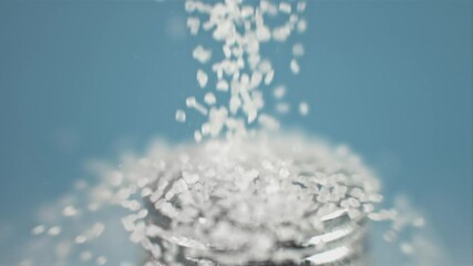 Poster - Super slow motion drop salt on a salt shaker, on a blue background. Filmed on a high-speed camera, 1000 fps. 