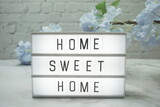 Fototapeta  - Home Sweet Home Word in light box with flowers decoration