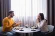 © LIGHTFIELD STUDIOS - Arabian man pointing at smiling girlfriend during dinner in restaurant