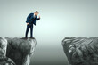 A man in a business suit stands on the edge of a cliff and looks down into the post. Business concept, crisis, bankruptcy, problems.