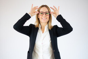 Amazed young pretty woman in checkered shirt touching her glasses