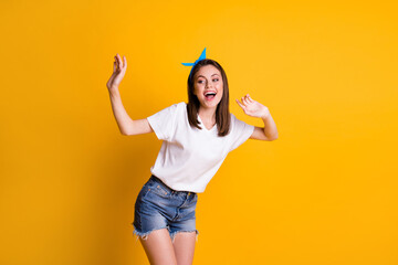 Wall Mural - Portrait of charming glad cheerful girl having fun dancing enjoying rest disco isolated over bright yellow color background