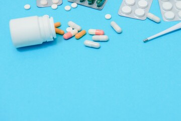 Wall Mural - Scattered white pills on blue table.Medical, pharmacy and healthcare concept. Blue background white pills with a medical statoscope, top view.