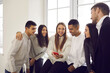 © Studio Romantic - Group of young cheerful different ethnicity people team or students classmates sitting on windowsill and looking on girls smartphone having fun together. International team, multi ethnic group concept