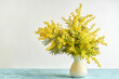 Vase with mimosa flowers on white background