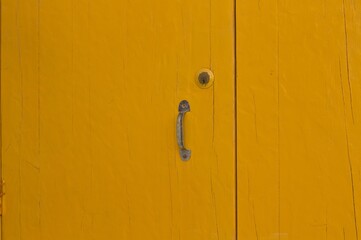 Wall Mural - A yellow wooden door background with a rusted iron handle (Pesaro, Italy, Europe)