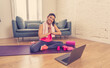 © SB Arts Media - Attractive woman on laptop in virtual online fitness class working out at home