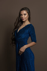 Perfect brunette woman in blue evening dress on brown background