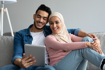 Wall Mural - Happy middle-eastern couple looking at digital tablet screen