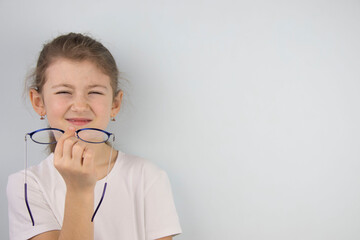 little girl wipes tired eyes from glasses, cute child feeling discomfort and fatigue,tired after long wearing spectacles,eyesight problem,isolated on white background,eye fatigue