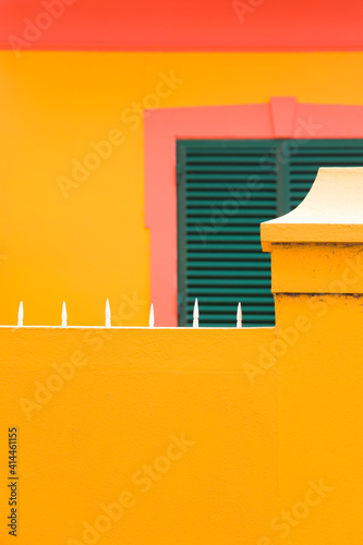 Obraz Dibond Colorful vintage building with green window shutters on yellow wall