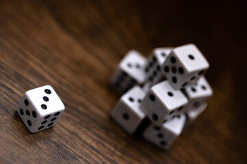 top view of dice on wood table showing a three with a stack of dice in the background