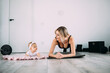 Happy mom and daughter on the floor in the room doing physical exercises on the gymnastic mat at home. Fitness and recovery concept after childbirth.