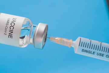 Wall Mural - Vaccine vial with syringe isolated over blue background. Medical concept shows a medical vial and coronavirus vaccines coronavirus