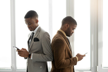 two handsome african men in suits at the office with mobile phones 